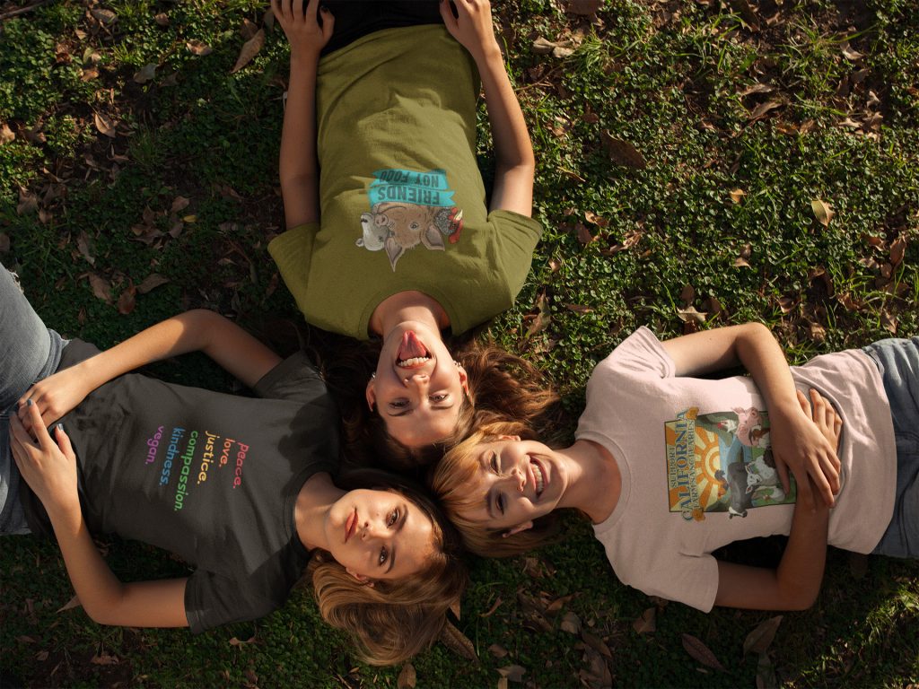 Girls wearing Little Hill Sanctuary shirts smiling on grass