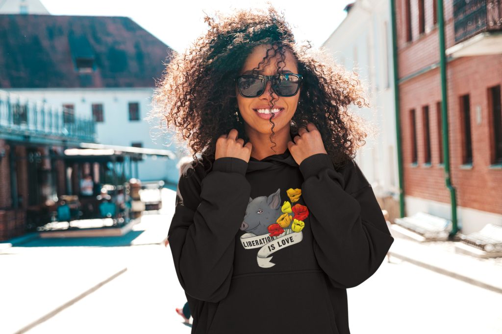 Girl with sunglasses wearing a black hoodie with a pig and flowers on it
